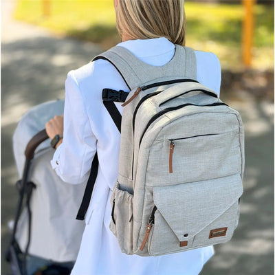Beige Primo Passi PerTutti Baby Diaper Bag Backpack worn by a woman, featuring multiple pockets and adjustable straps.
