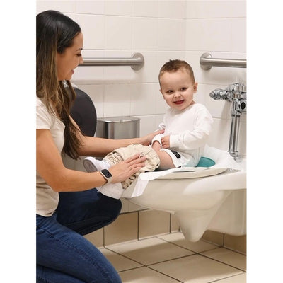 A woman assists a smiling toddler on a toilet training seat in a bathroom, demonstrating the Prince Lionheart Tinkle To Go product.