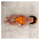 African American full silicone reborn baby doll Arianna, wearing an orange dress with floral designs and a matching headband.