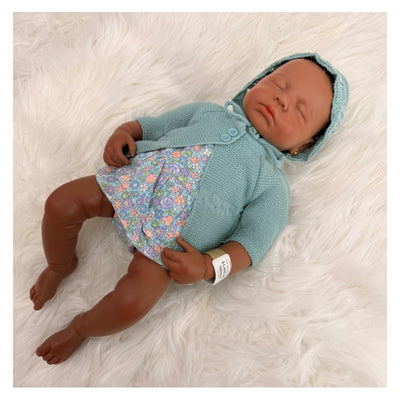 Reborn baby doll named Emily, with African American features, wearing a colorful floral dress and a knitted hoodie.
