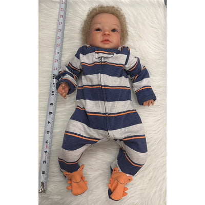 Reborn baby doll Shyann with curly hair, wearing a striped onesie with orange-accented feet.