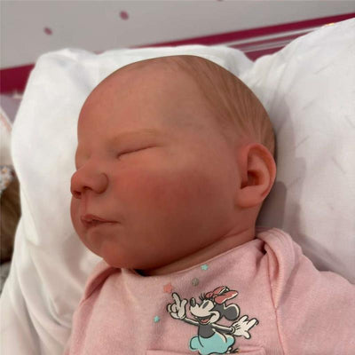 Reborn Baby Doll named Jasmine with white vinyl skin, wearing a light pink outfit featuring a cartoon character.