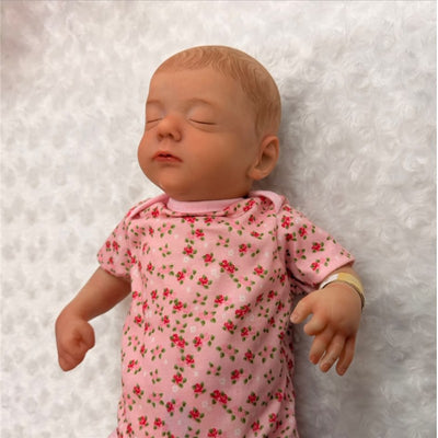 Reborn Baby Doll Marnie 2, featuring white vinyl, sleeping pose, and pink floral outfit.