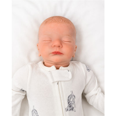 Reborn Baby Doll named Marnie, made of white vinyl, wearing a gray-accented white onesie, eyes closed.