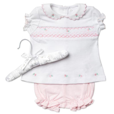Short-sleeve white top with pink floral embroidery paired with pink ruffled shorts, displayed on a hanger.