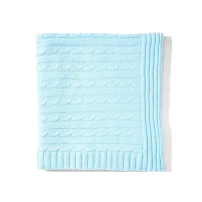 Cable knit blanket in a soft blue color, featuring textured patterns and a ribbed edge design.