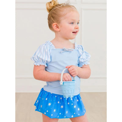 Baby girl wearing a blue puffed sleeve swimsuit with a star-patterned skirt, holding a light blue bucket.