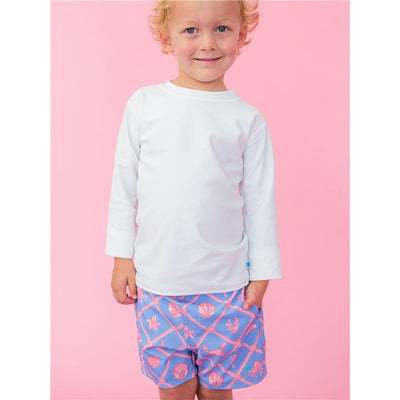 Boys wearing white long-sleeve rash guard and blue swim trunks with pink tropical shell patterns against a pink background.