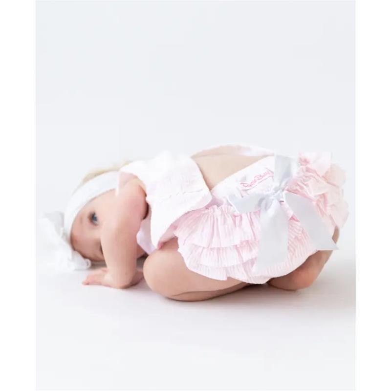 Baby girl wearing a pink seersucker swing top and bloomer set with ruffles and a bow, crawling on the floor.