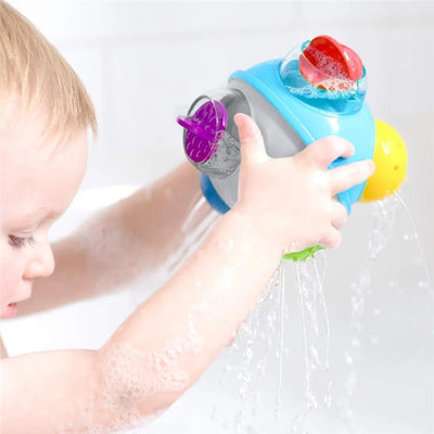 A child bathes in water, holding a colorful Sassy Rain Shower Bath Ball with water pouring from it.