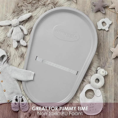 Squishy grey baby changing diaper pad with a non-toxic PU Foam surface, surrounded by soft toys and clothing items.