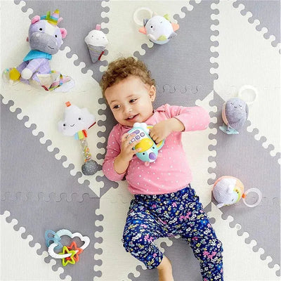 Child playing with the Skip Hop Zoo Baby Cell Phone Toy, surrounded by colorful plush toys on a patterned play mat.