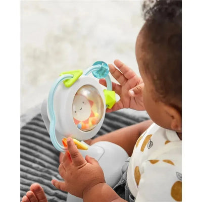 Baby in a seated position engages with a colorful toy featuring a clear dome and a smiling lion design, stimulating play and exploration.