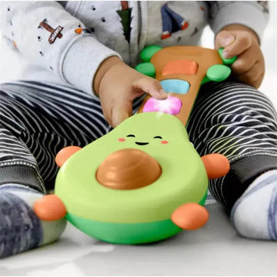 Baby playing with the Skip Hop Farmstand Rock-A-Mole Guitar, featuring colorful buttons and a smiling avocado design.
