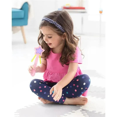 Young girl in pink shirt and polka dot leggings playing with a pink and purple star wand toy while sitting on the floor.