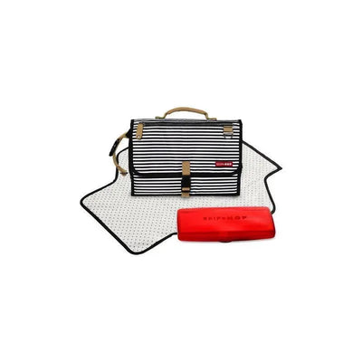 Portable baby changing pad by Skip Hop in black and white stripes, with a red case and polka-dot mat laid out.