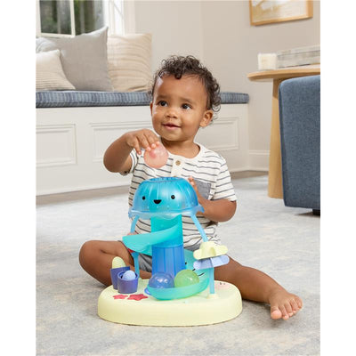 Toddler playing with the Skip Hop Seascape Musical Activity Ball Drop, holding a ball above a colorful, interactive structure.