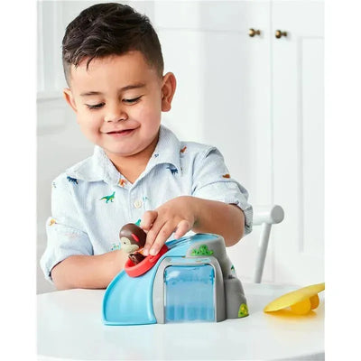 Young boy playing with the Skip Hop Zoo Outdoor Adventure Playset, featuring a monkey toy and a water slide.