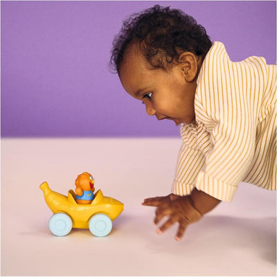 Baby reaching for a yellow toy vehicle with a pull-along design and a click-in figure smiling from the seat.