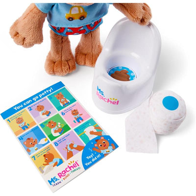Plush teddy bear dressed in blue and red, with a mini potty, a roll of toilet paper, and a colorful instructional card.