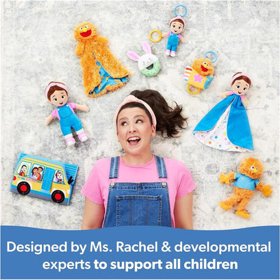 Ms. Rachel smiles surrounded by colorful toys, including her Speak N Sing Doll, promoting developmental support for children.
