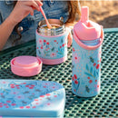 Insulated stainless steel bottle with handle and floral design, alongside a food container, on a picnic table.