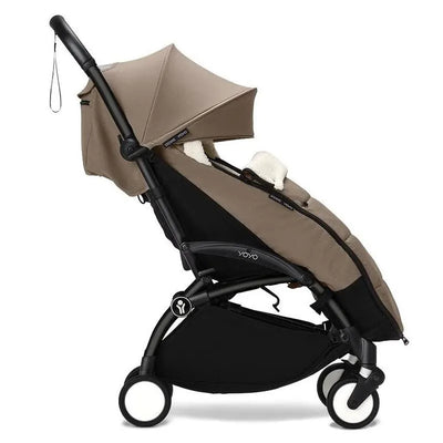 Taupe Babyzen Yoyo footmuff attached to a black stroller, providing warmth and comfort for infants during outings.