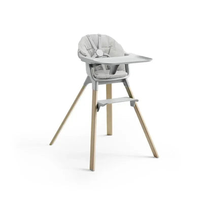 Stokke Clikk Cushion in Nordic Grey, featuring a highchair design with a padded seat and wooden legs.