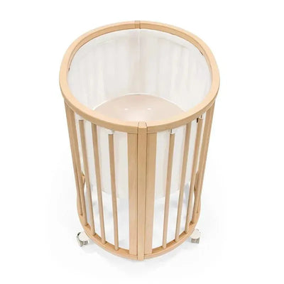 Stokke Sleepi Mini Mesh Liner in white, designed for a circular crib with wooden slats and castors for mobility.