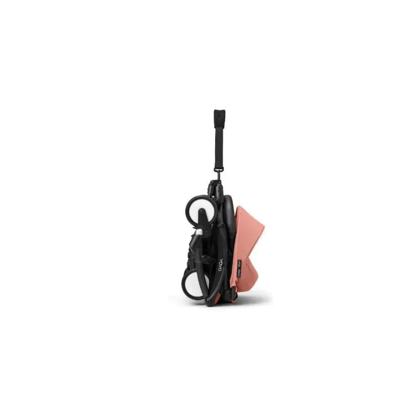 Stokke Yoyo³ stroller in a folded position, featuring a black frame and ginger-colored fabric, designed for children 6+.