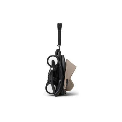 Folded Stokke Yoyo³ stroller in black with taupe fabric, featuring a carrying strap and compact design for easy transport.