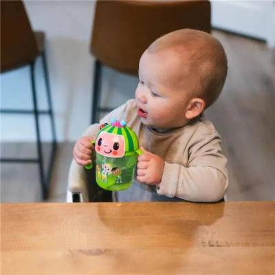 Cocomelon Weighted Straw Trainer Cup held by a toddler, featuring colorful characters and a playful design.