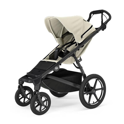 Thule Urban Glide 4-Wheel Single Child All-Terrain Stroller in soft beige, featuring a reclining seat, adjustable canopy, and large wheels.