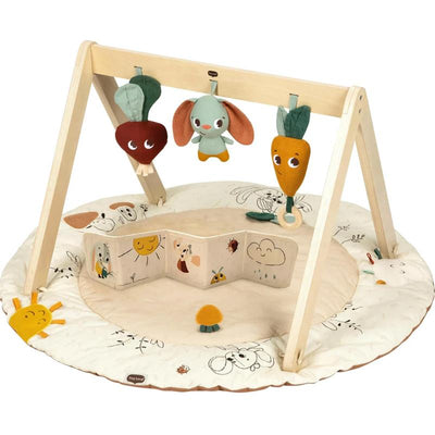 Tiny Love Gymini activity mat with a wooden frame, featuring colorful plush toys, a soft play mat, and an interactive fabric book.