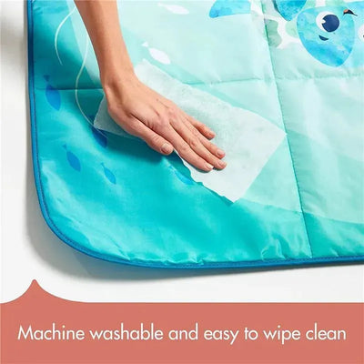 A hand wipes a colorful, ocean-themed picnic mat, highlighting its machine-washable and easy-clean features.