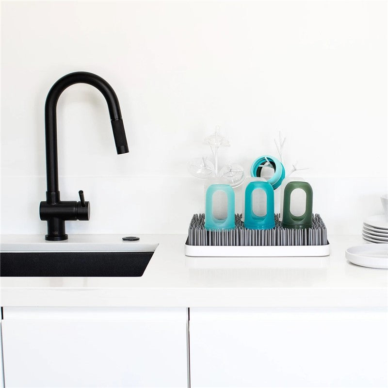 Boon LAWN drying rack with two TWIG accessories, featuring colorful drying cups and a modern kitchen faucet on a white countertop.