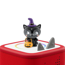 Black cat figurine with a purple witch hat and a pumpkin candy bucket atop a red audio toy, designed for Halloween songs.