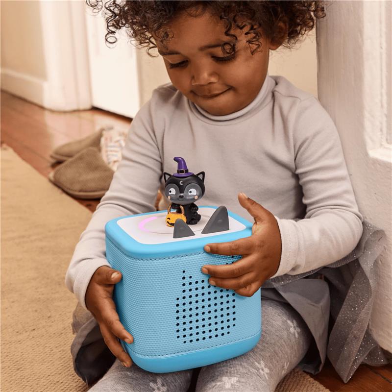 Child holding a blue audio toy with a black cat figurine wearing a witch hat, designed for Halloween songs.