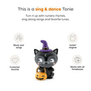 Black cat figurine wearing a purple witch hat, holding a pumpkin bag, featuring Halloween songs for children.