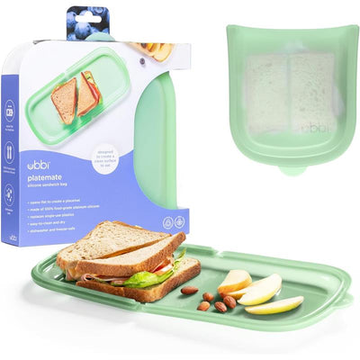 Reusable silicone storage bag by Ubbi, shown with a sandwich and snacks on a green placemat.