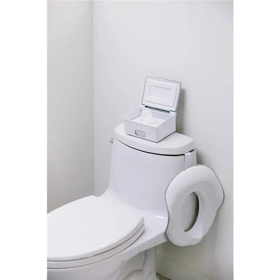 Ubbi flushable wipes dispenser in white and grey placed on a toilet tank, with an open lid showing wipes inside.