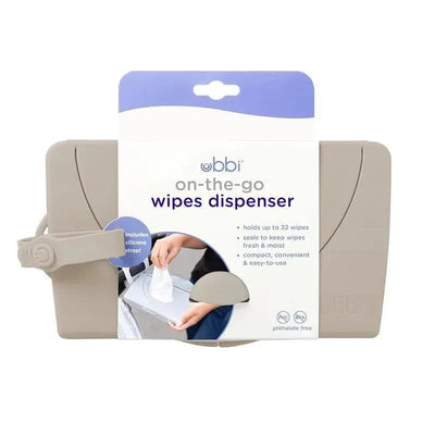 Ubbi on-the-go baby wipes dispenser in taupe, showcasing a hand pulling a wipe, includes a silicone strap, holds 22 wipes.