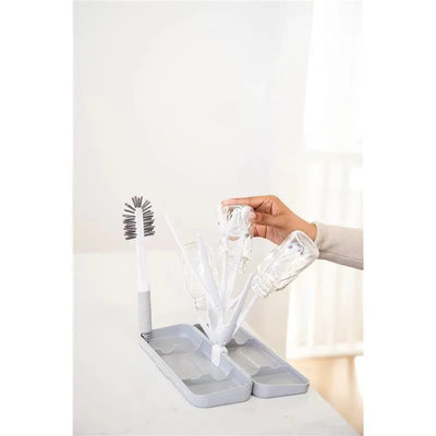 On-the-Go Drying Rack in grey with four clear bottles drying on white arms and a bottle brush on a base.