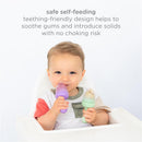 Toddler in a high chair holding a purple and green Ubbi baby food feeder, enjoying self-feeding with a teething-friendly design.