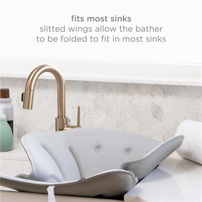 Soft gray Ubbi Stingray Sink Bather designed for babies, featuring slitted wings for folding to fit most sinks.
