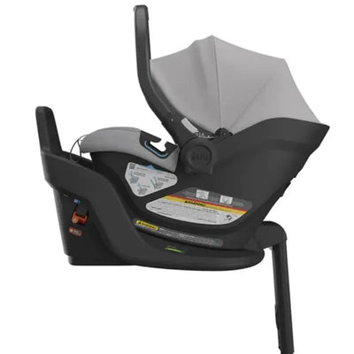 Light grey Uppababy Aria Infant Car Seat with an adjustable canopy and clear safety instructions on the side.