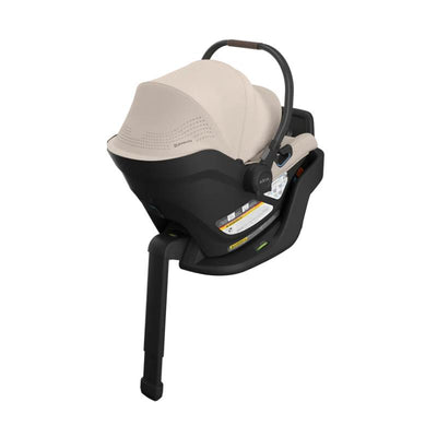 Uppababy Aria V2 Infant Car Seat in Sandstone Melange with Chestnut Leather, featuring an adjustable handle and safety labels.