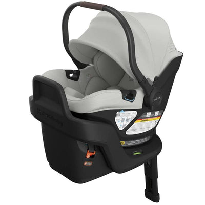 Lightweight Uppababy Aria V2 infant car seat in Pearl Gray Melange, featuring a safety label, adjustable handle, and reclined base.