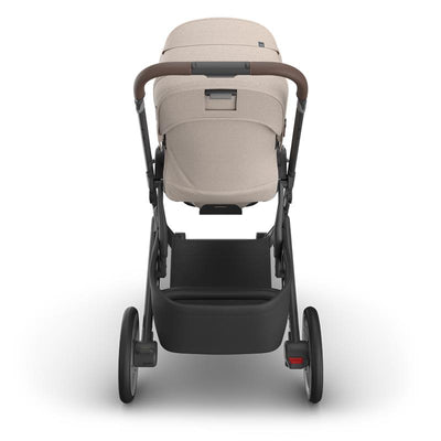 Uppababy Cruz V3 stroller in Sandstone Melange with Chestnut Leather handle, viewed from the back, showcasing the seat and wheels.