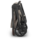 Uppababy Kona stroller in folded position, featuring a sandstone mélangé fabric and sleek black frame.